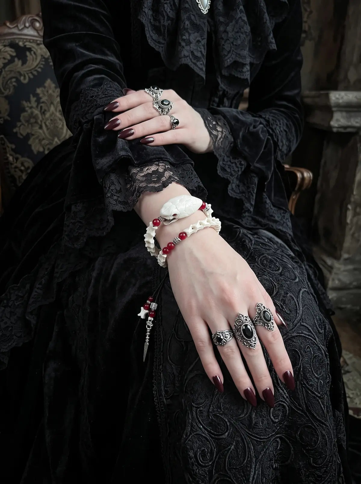 Bloodlance Snake Bone Bracelet, close wrist view of preserved pale snake head and red beads with dangling charms