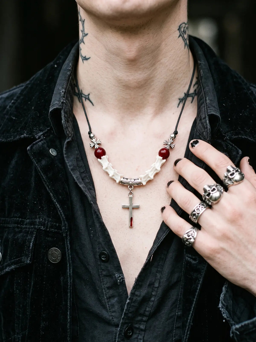Bloodmark Cross Snake Bone Necklace, white snake bone necklace with crimson bead details over a black jacket
