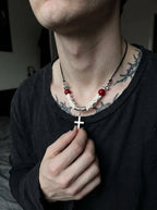 Bloodmark Cross Snake Bone Necklace, close view of pale vertebrae and dangling cross held by a model wearing black