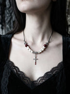 Bloodmark Cross Snake Bone Necklace, silver cross pendant and red beads displayed on a snake bone necklace