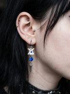 Blue Shard Snake Bone Earrings, blue bead and star-decorated snake bone earring worn on an ear in side view