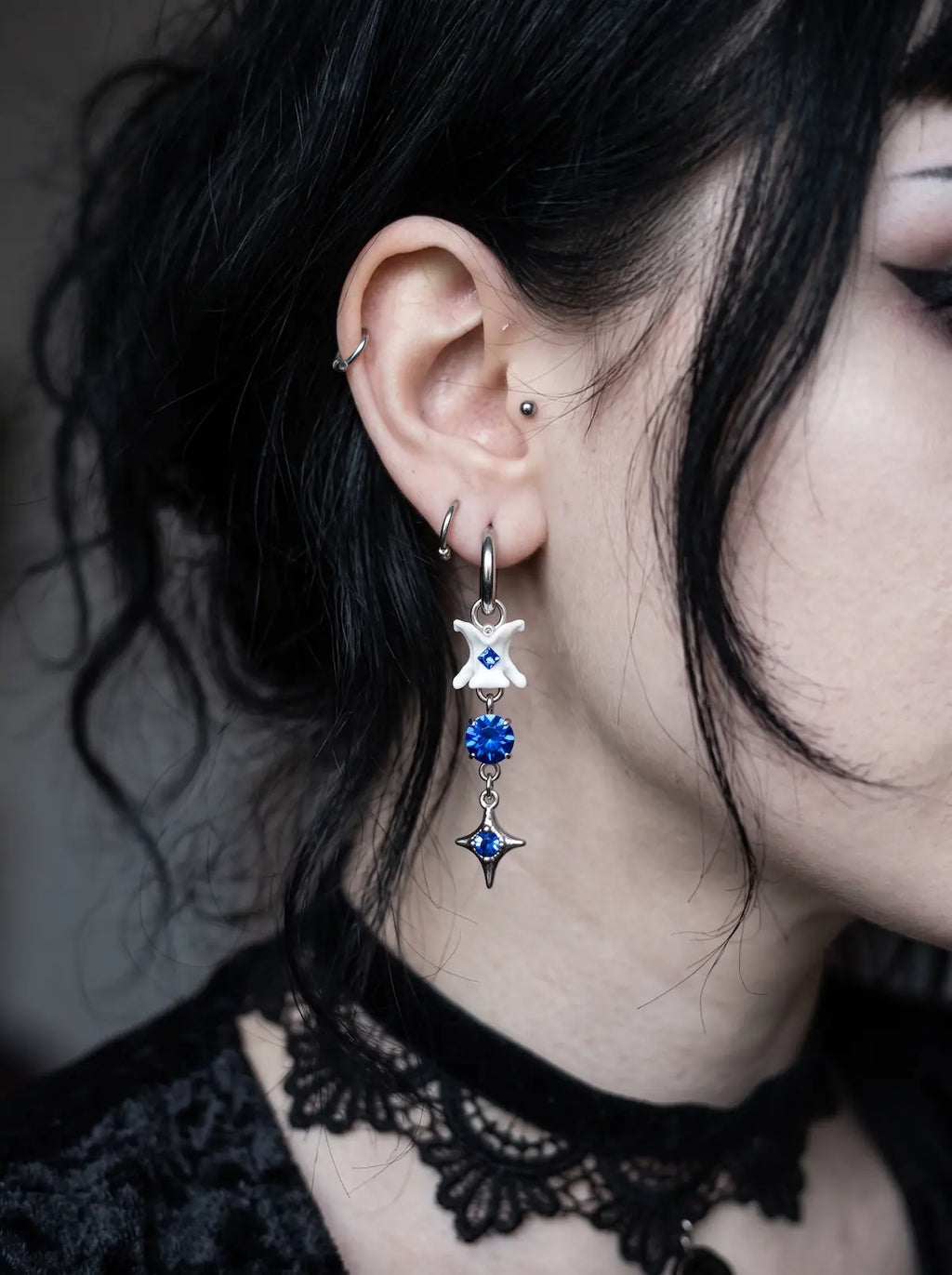 Blue Shard Snake Bone Earrings, side profile wearing a pale vertebrae earring with vivid blue bead details