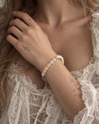 Blush Arc snake bone bracelet worn with the hand near the collarbone above a cream lace neckline