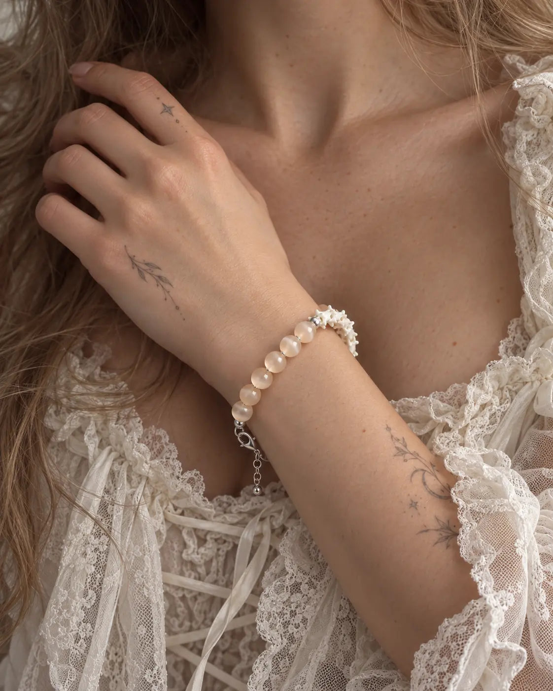 Blush Arc snake bone bracelet worn with the hand near the collarbone above a cream lace neckline