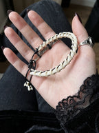 Bonebound Snake Bone Bracelet, snake vertebrae and black cord bracelet laid across an open palm