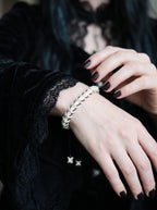 Bonebound Snake Bone Bracelet, slender snake vertebrae bracelet worn on a wrist against black clothing