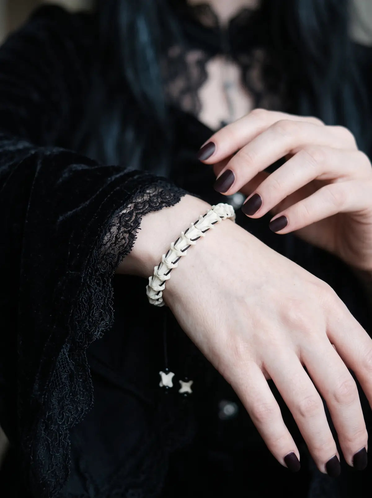 Bonebound Snake Bone Bracelet, slender snake vertebrae bracelet worn on a wrist against black clothing