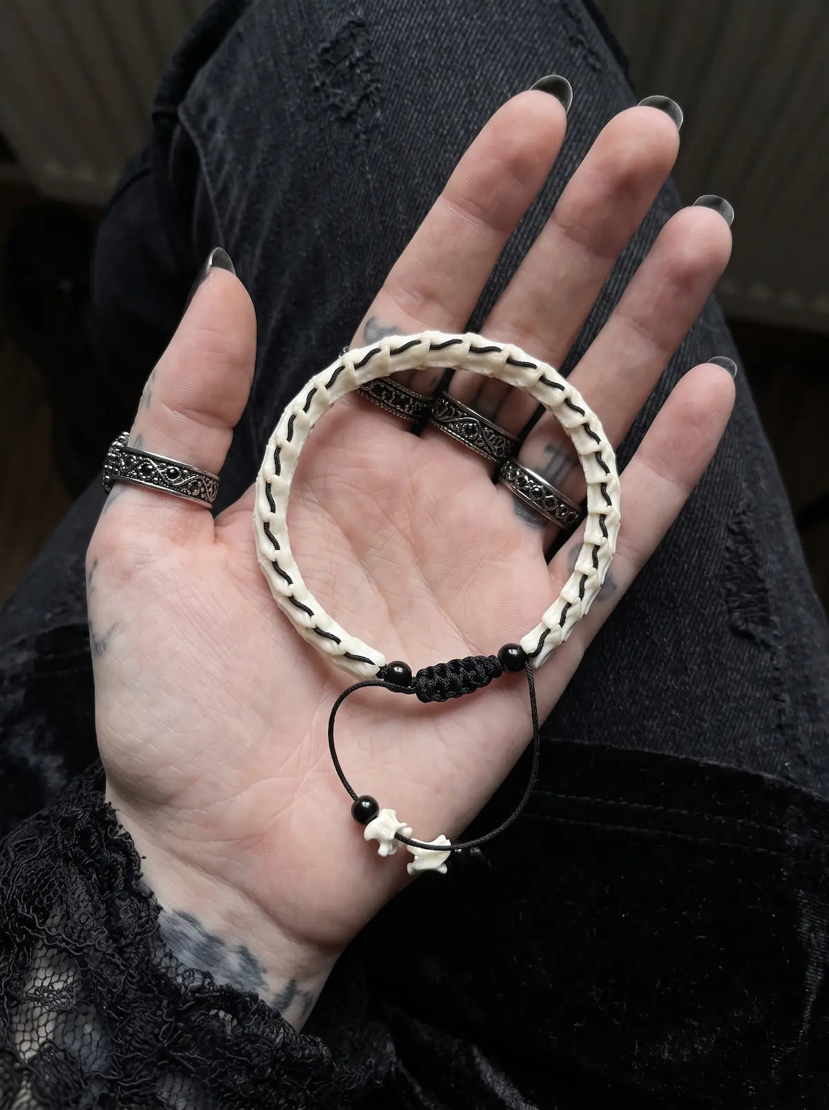 Bonebound Snake Bone Bracelet, coiled vertebrae bracelet in an open palm showing its adjustable cord closure