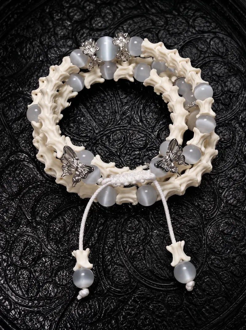 Butterfly Mist layered snake bone bracelet with pale gray beads, silver-tone butterflies and white beaded cord ends