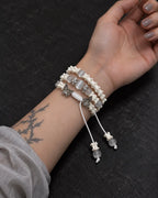 Palm-up view of the Butterfly Mist snake bone bracelet showing three rows and white beaded cord ends