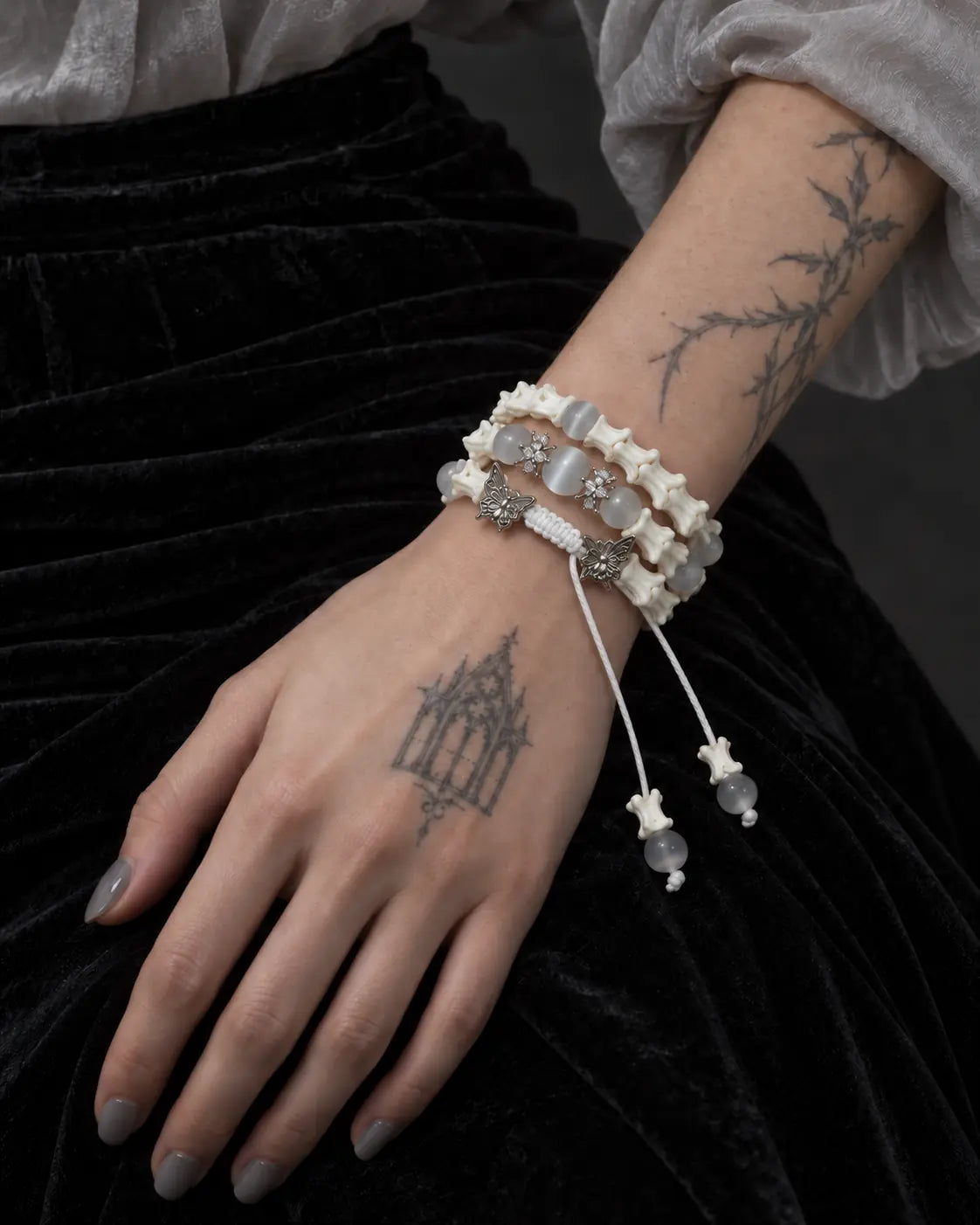 Butterfly Mist snake bone bracelet worn on a wrist resting against black velvet