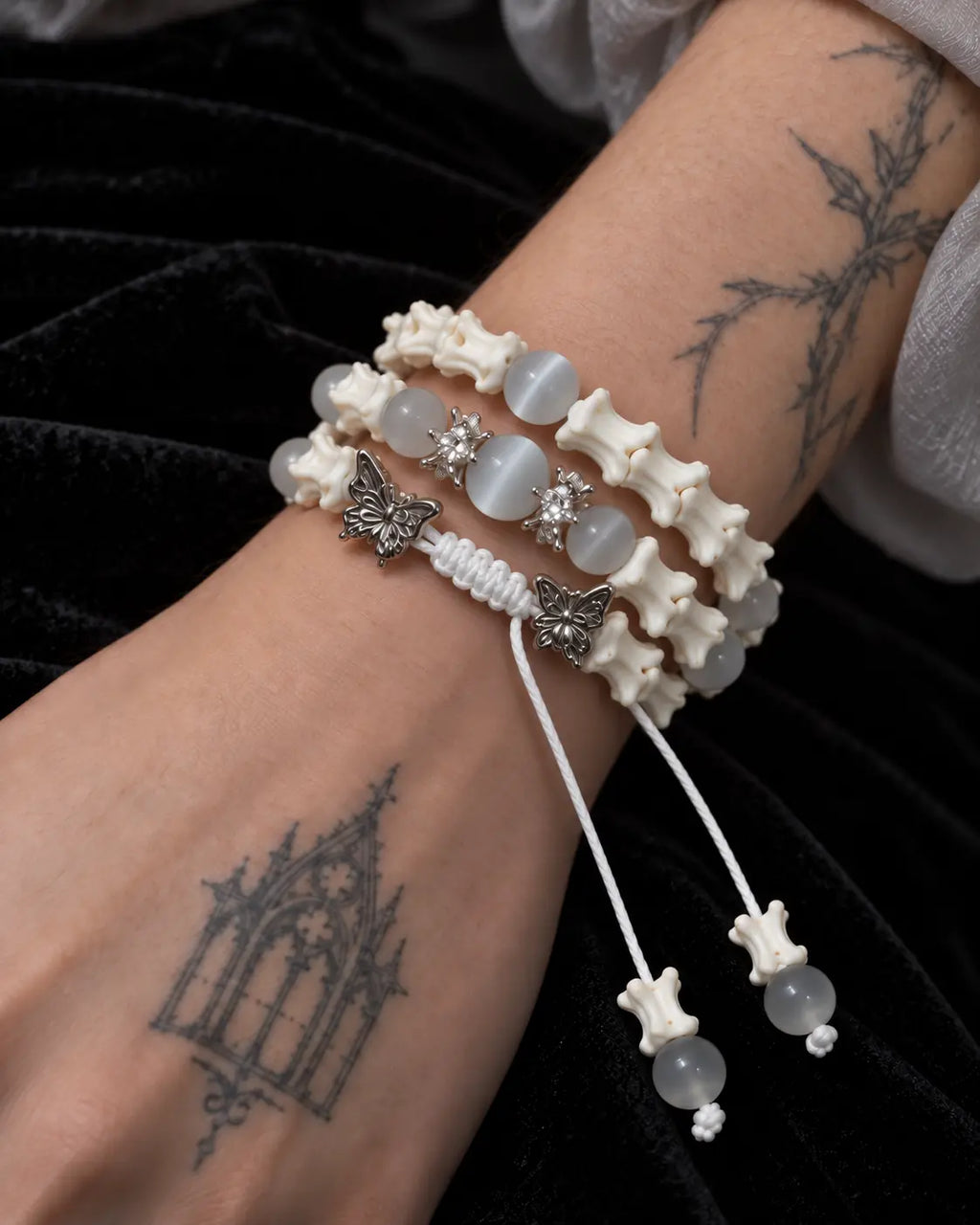 Close-up of the Butterfly Mist snake bone bracelet showing gray beads, butterfly accents and its white braided knot