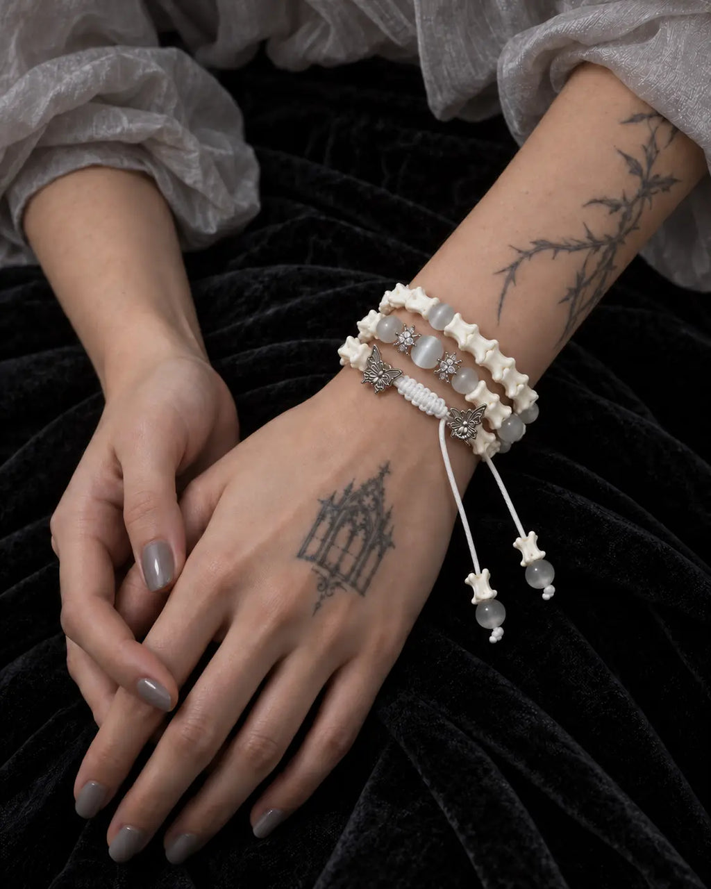 Butterfly Mist snake bone bracelet shown with one hand resting over the other on a black velvet skirt