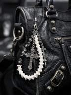Cathedral Relic Snake Bone Keychain, snake bone keychain with dangling metal charms attached to a black leather bag