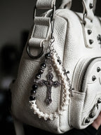 Cathedral Relic Snake Bone Keychain, snake bone and silver-tone cross keychain held in a hand to show the full loop