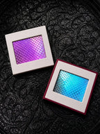 Purple and blue Chromatic Relic snakeskin bookmark charms in white square frames on black patterned fabric