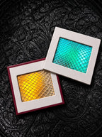 Turquoise and golden yellow Chromatic Relic snakeskin bookmark charms in overlapping square frames on black fabric