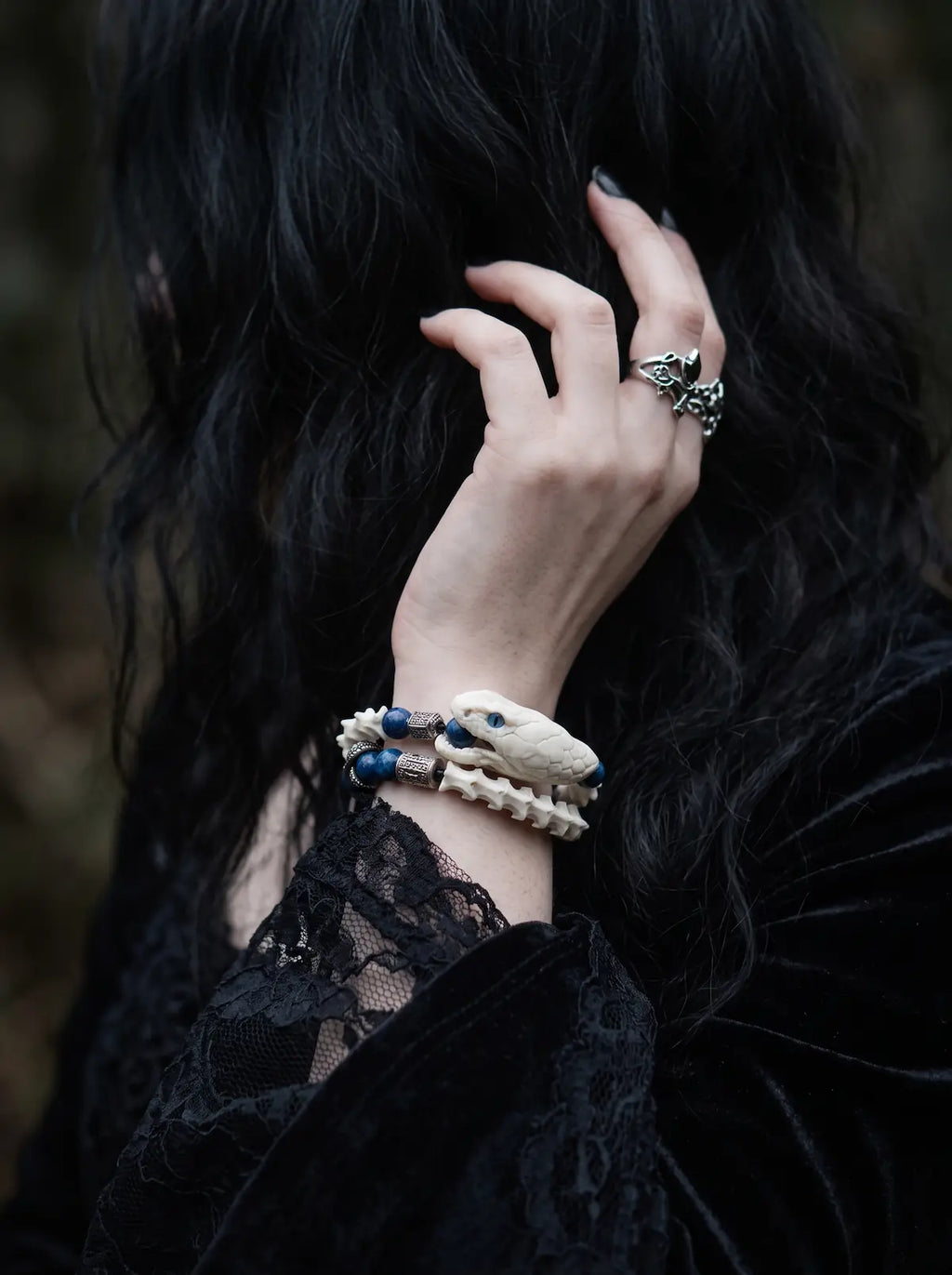 Cobalt Batwing Snake Bone Bracelet, wrist wearing white bone bracelet with bright blue beads and dangling charms
