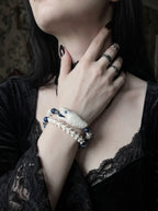 Cobalt Batwing Snake Bone Bracelet, white vertebrae bracelet with blue beads worn while a hand rests near the neck