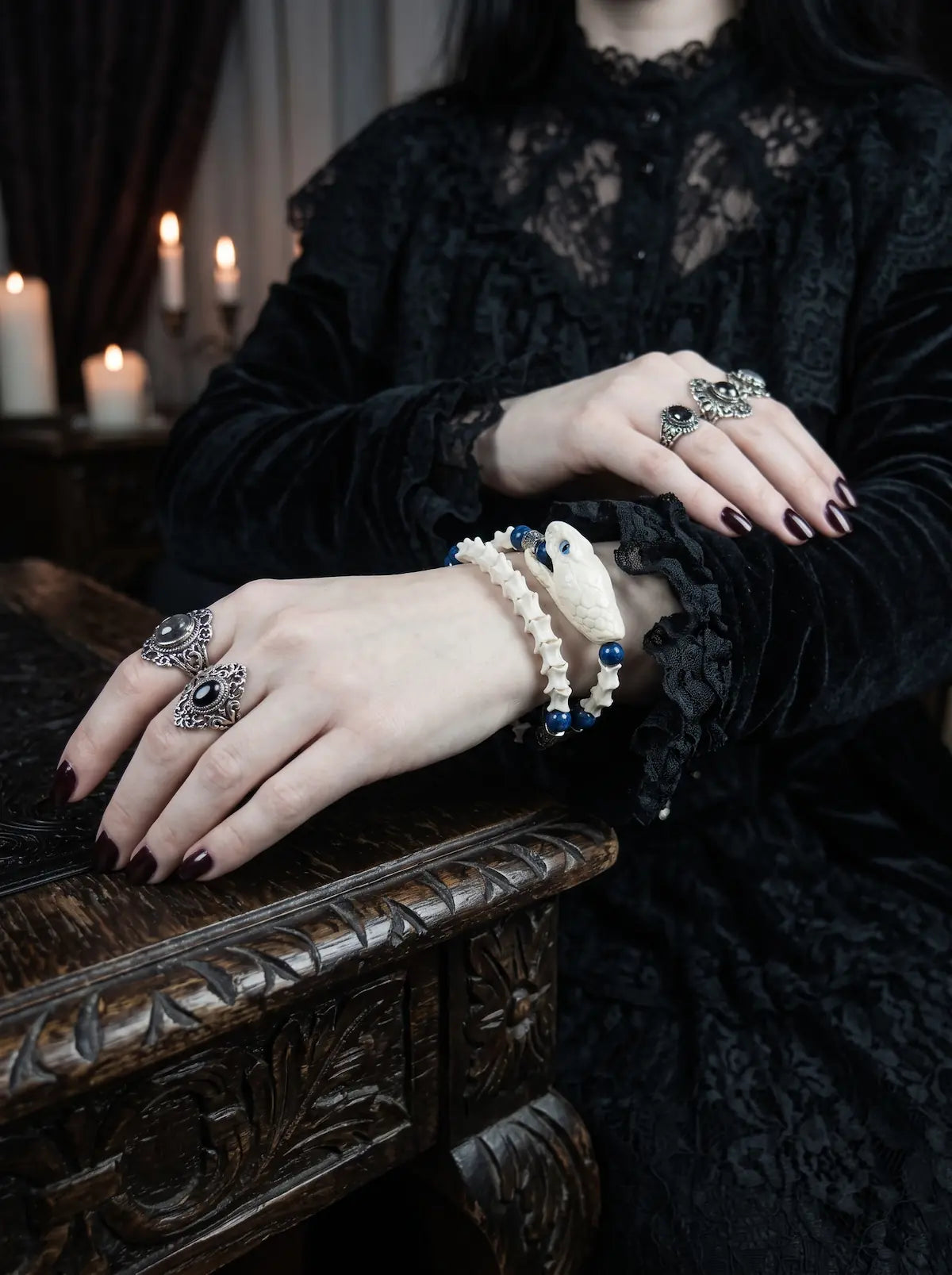 Cobalt Batwing Snake Bone Bracelet, wrist showing cobalt bead accents and black cord against a gothic lace outfit