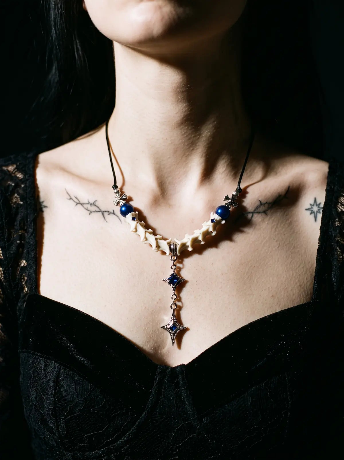 Cobalt Starfall Snake Bone Necklace, blue bead and white snake bone necklace worn at the neckline of a black outfit