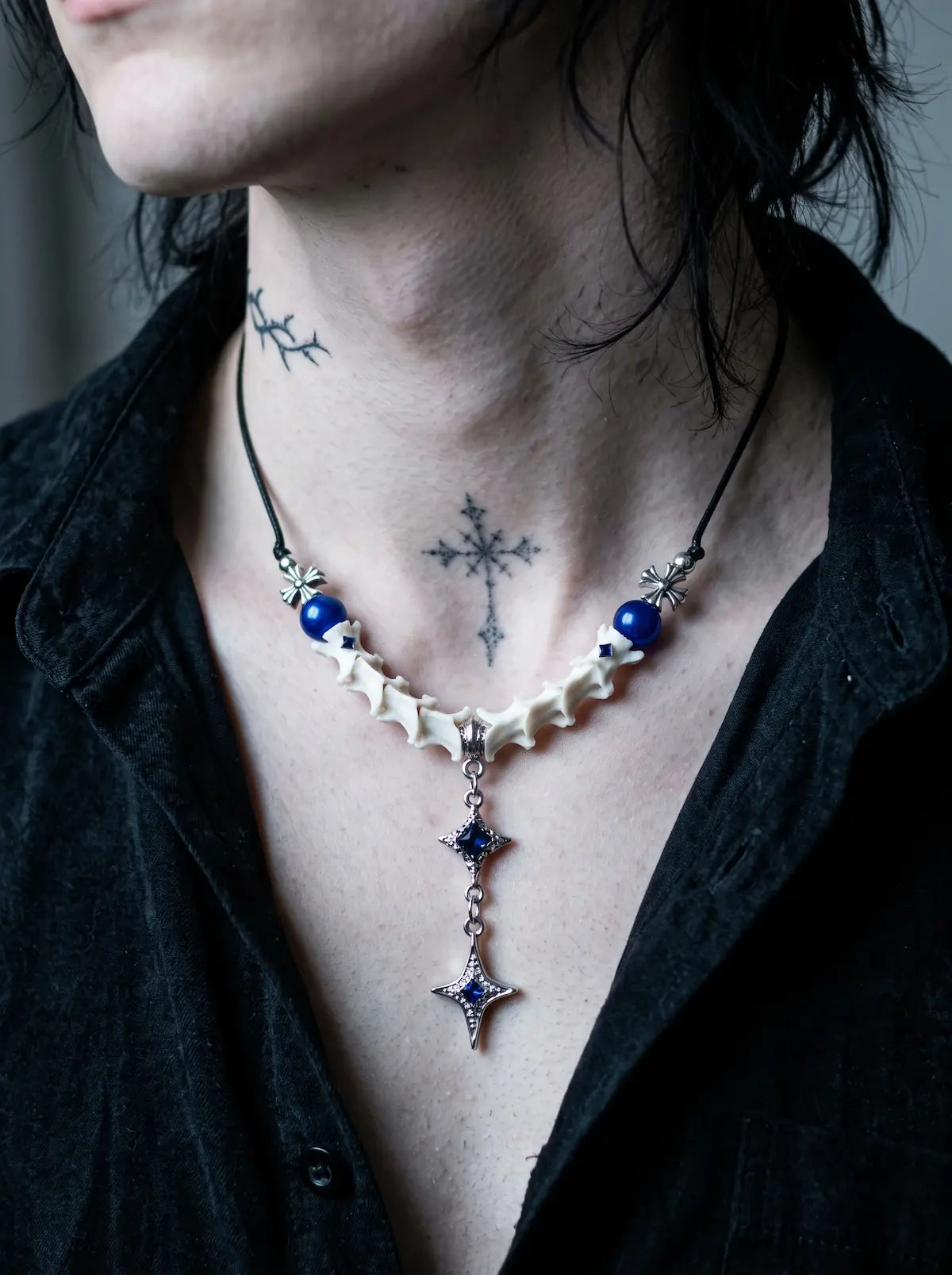 Cobalt Starfall Snake Bone Necklace, front neck close-up showing a pointed star pendant below pale vertebrae