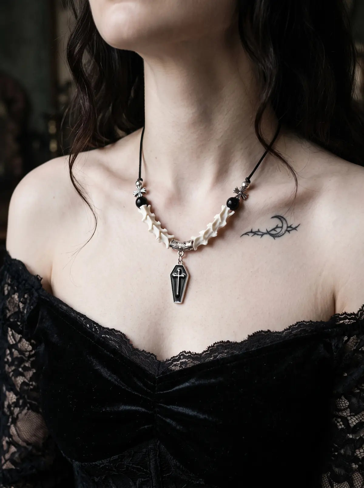 Coffin Oath Snake Bone Necklace, front view of coffin charm and pale snake bone necklace on a model in black