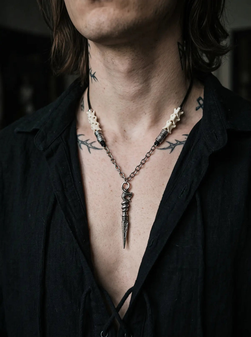 Coilblade Snake Bone Necklace, snake bone and dagger necklace worn at the chest under an open black shirt