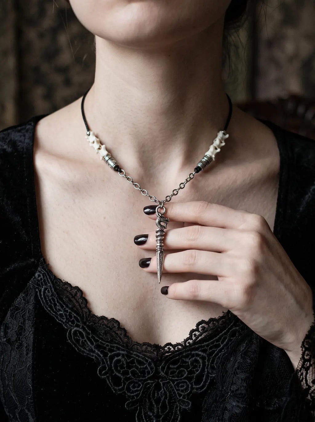 Coilblade Snake Bone Necklace, white bone necklace with dagger charm worn above a black velvet neckline