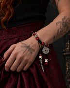Crimson Coin snake bone bracelet worn on a wrist resting against a burgundy patterned skirt