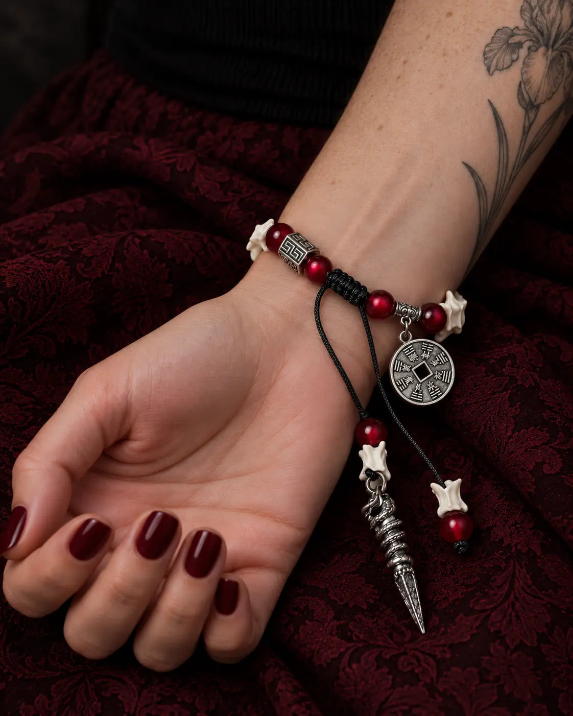 Palm-up close-up of the Crimson Coin snake bone bracelet showing its coin, red beads and black sliding knot
