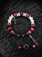 Crimson Cross snake bone bracelet with red beads, a silver-tone cross, dark rose and long pointed pendant on black cords