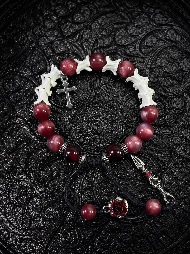 Crimson Cross snake bone bracelet with red beads, a silver-tone cross, dark rose and long pointed pendant on black cords