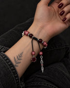 Palm-up view of the Crimson Cross snake bone bracelet showing the sliding knot and dangling rose and pointed pendant