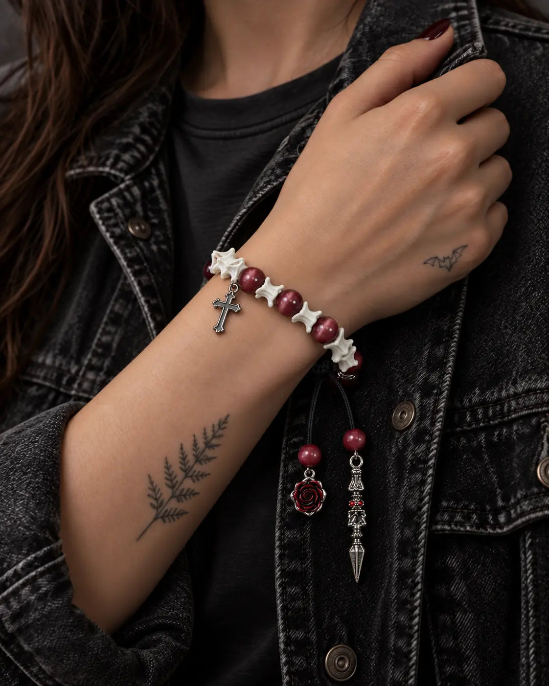 Crimson Cross snake bone bracelet worn with the hand holding a black denim jacket collar