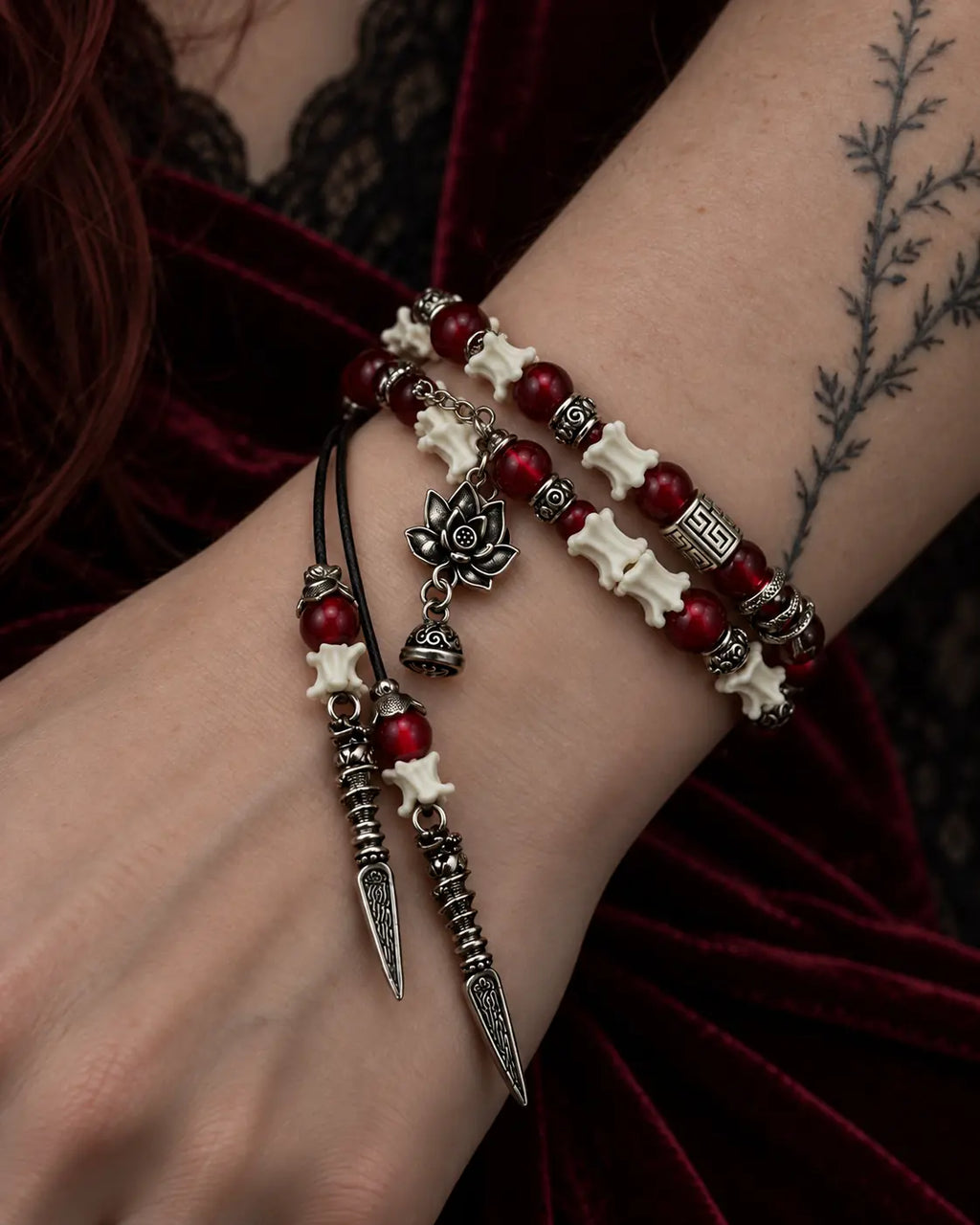 Close-up of the Crimson Lotus snake bone bracelet showing two strands, red beads, a lotus charm and pointed drops