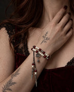 Crimson Lotus snake bone bracelet worn with the hand near the neck above a burgundy velvet neckline
