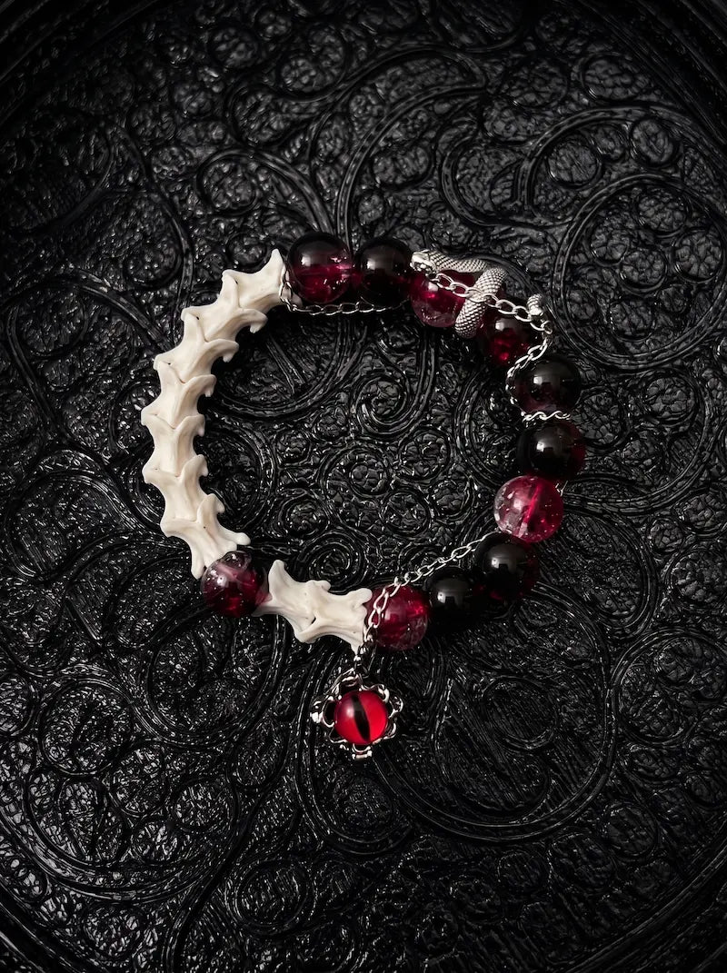 Crimson Serpent Eye snake bone bracelet with red and black beads, a silver-tone serpent and a red reptilian eye charm