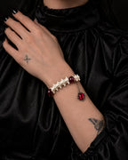 Crimson Serpent Eye snake bone bracelet worn with the hand at a black satin collar, showing the dangling red eye