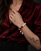 Crimson Spine snake bone bracelet worn with the hand at the collar of a burgundy satin blouse