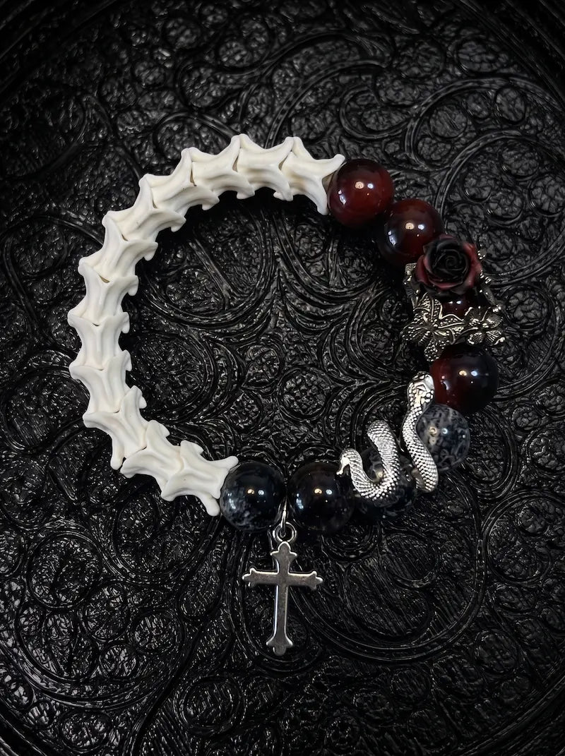 Crimson Thorn snake bone bracelet with red and smoky black beads, a dark rose, silver-tone serpent and cross charm