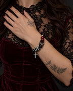 Crimson Thorn snake bone bracelet worn with the hand against a black lace neckline above burgundy velvet
