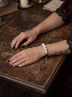Crimson Thorn snake bone bracelet shown from the bone side with both hands resting on a worn wooden table
