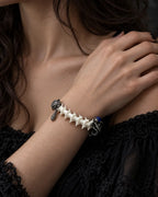 Duskdrake Snake Bone Bracelet, white spine bracelet worn on a hand resting on the model's shoulder