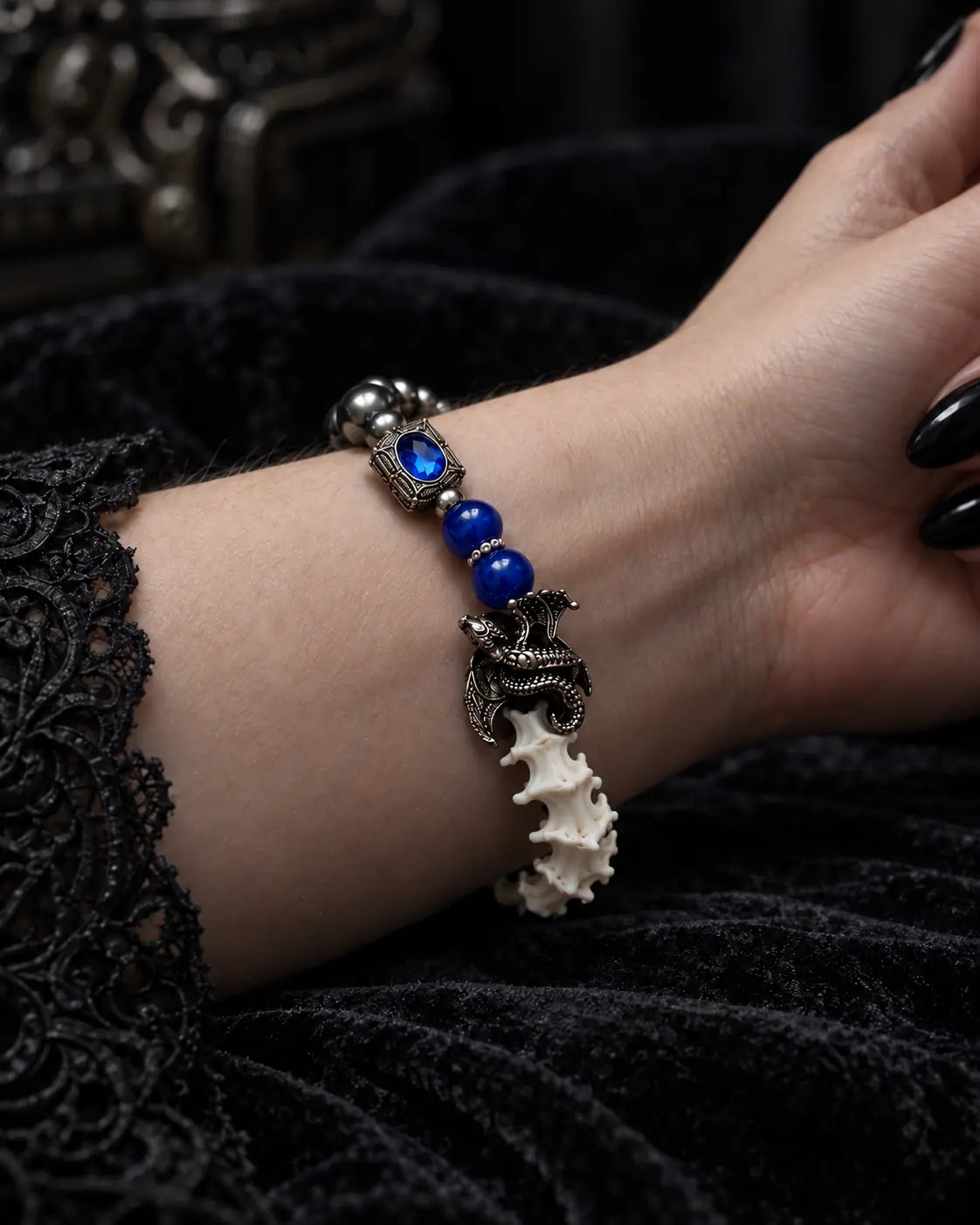 Duskdrake Snake Bone Bracelet, close wrist angle of blue beads and ornate dark clasp on the bone bracelet