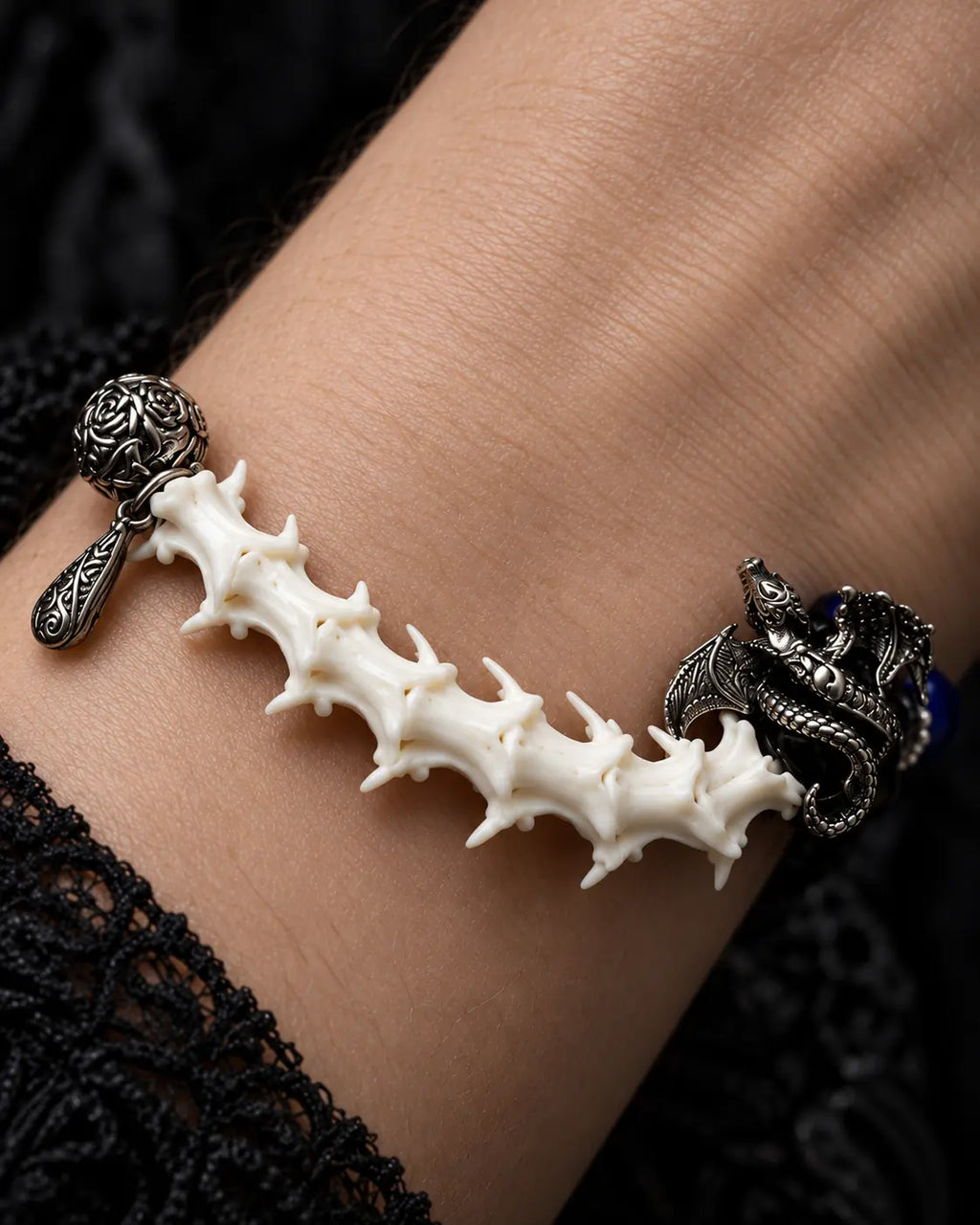 Duskdrake Snake Bone Bracelet, macro view of white vertebrae section and textured dark metal dragon-style accents