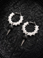 Ebon Thorn snake bone hoop earrings with matte black beads and silver-tone spikes on black patterned fabric