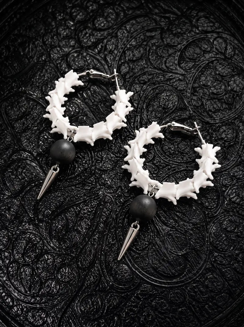 Ebon Thorn snake bone hoop earrings with matte black beads and silver-tone spikes on black patterned fabric