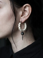 Close-up side view of an Ebon Thorn snake bone hoop earring with a black bead and pointed drop