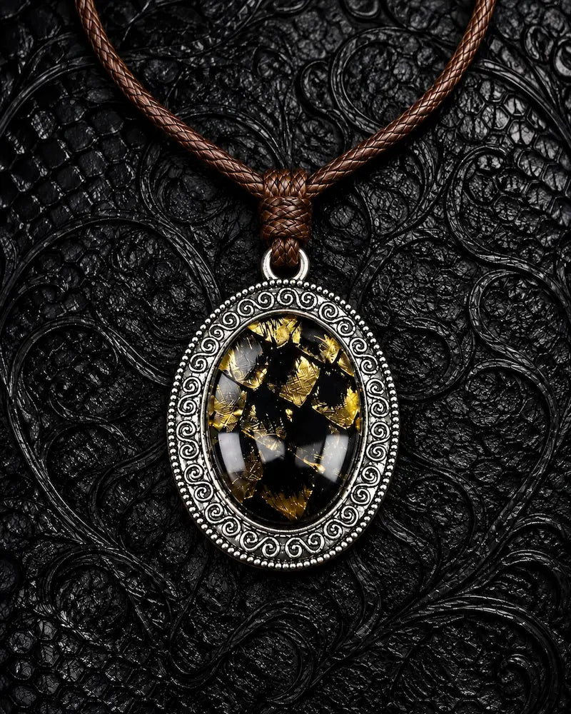 Eclipse Relic snakeskin pendant necklace in Gilded Black, showing black and gold scales within an ornate oval frame
